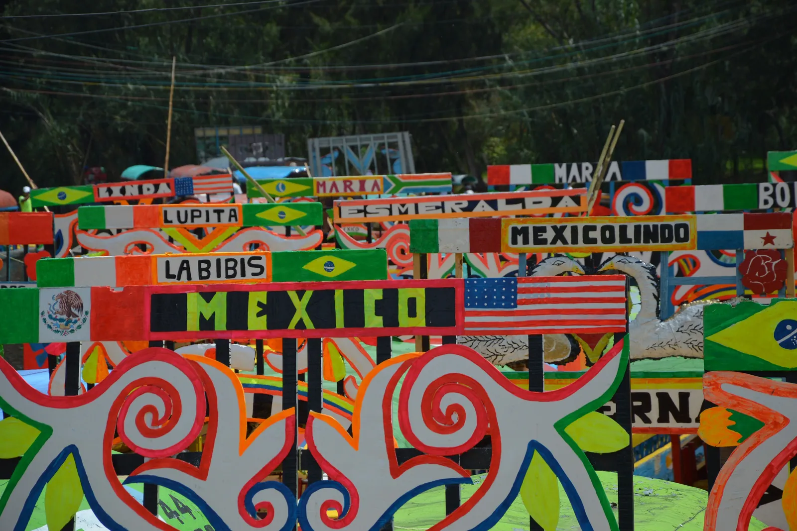 Nærbillede af trajinera-navnebuer ved en anløbsplads i Xochimilco, malet med blomster, flag og kvindenavne